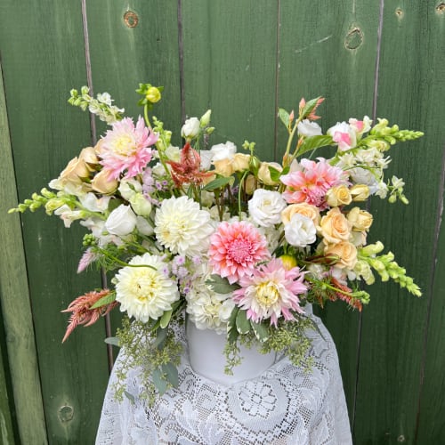 Mixed bouquet of pink, white, and peach flowers in a white vase