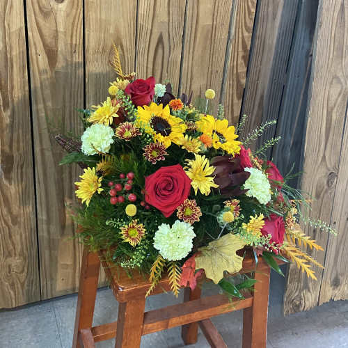 Bouquet of red roses, sunflowers, and mixed mums in a rustic arrangement