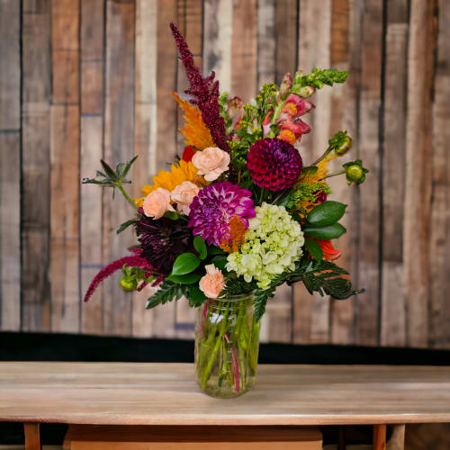Colorful mixed bouquet in a clear glass vase on a wooden table