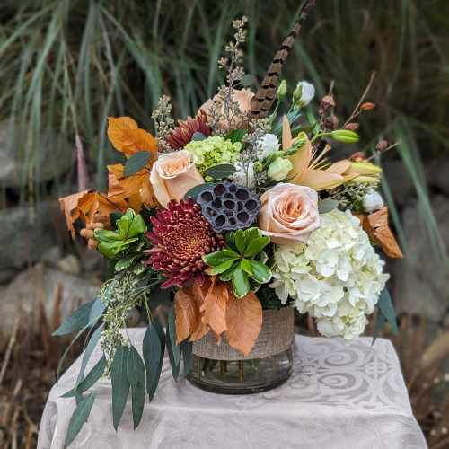 Autumn floral arrangement with roses, hydrangea, and chrysanthemums in a glass vase