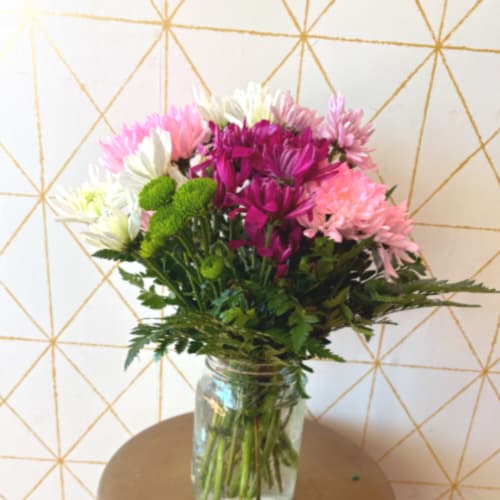 Bouquet of pink, white, and purple flowers in a glass jar vase