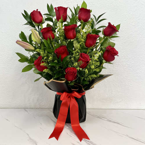 Bouquet of red roses with lilies in a black wrap tied with a red ribbon