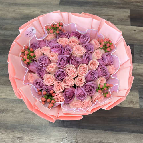 Round bouquet of pink and purple roses wrapped in pink paper