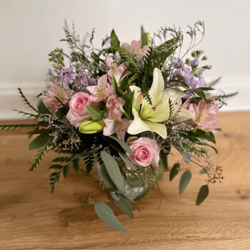 Pink roses and lilies arranged in a glass vase