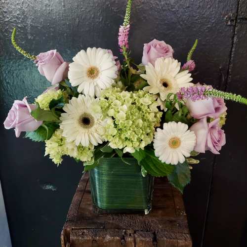 Lavender roses and white gerbera daisies in a green glass vase