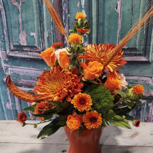 Orange floral arrangement in a red vase with chrysanthemums and roses