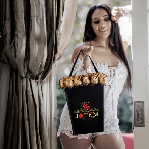 Woman in a white lace outfit holding a black flower box with gold roses