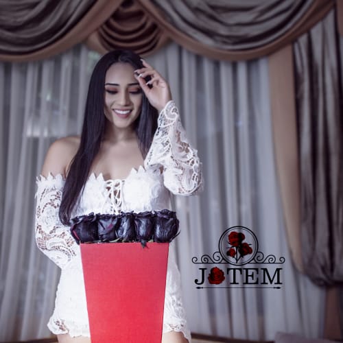 Woman in a white lace dress holding a red box of dark roses