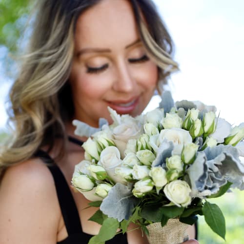 Woman holding a white rose bouquet with silver foliage