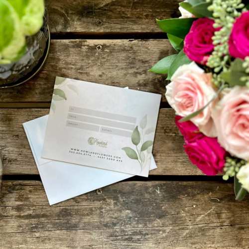 Gift card on a rustic wooden table beside flower arrangements
