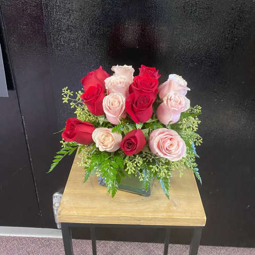 Pink and red roses arranged in a square glass vase
