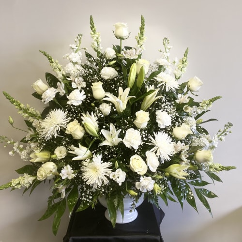 White floral arrangement in a white pedestal vase