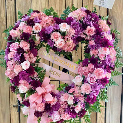 Heart-shaped floral wreath with pink and purple flowers and a ribbon