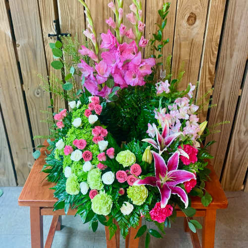 Tall pink floral arrangement with lilies and roses on a wooden table