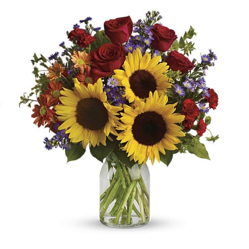 Bright bouquet of sunflowers, red roses, and mixed blooms in a clear glass jar vase