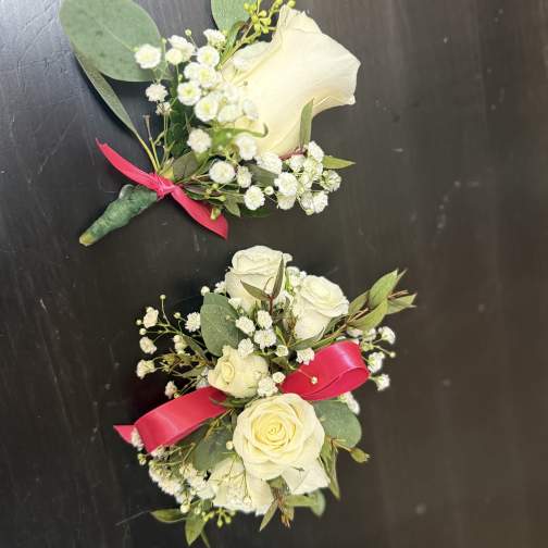 Two white rose boutonnieres with baby's breath and pink ribbon