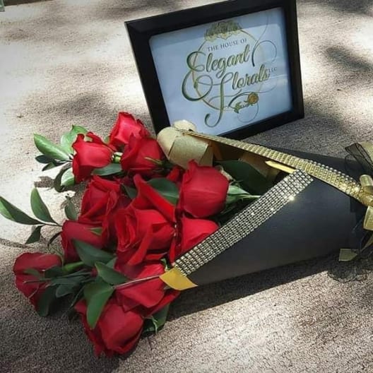 Bouquet of red roses wrapped in black paper with gold ribbon