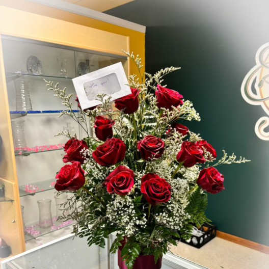 Red roses arranged in a vase with baby's breath and greenery
