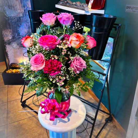 Pink and lavender roses arranged in a glass vase with a bright ribbon.