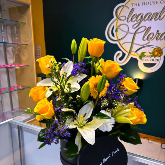 Yellow roses and white lilies arranged in a black box