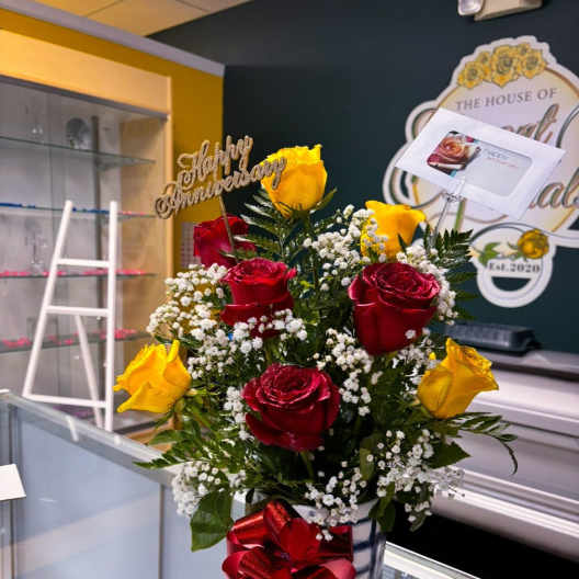 Bouquet of red and yellow roses in a glass vase with a red bow