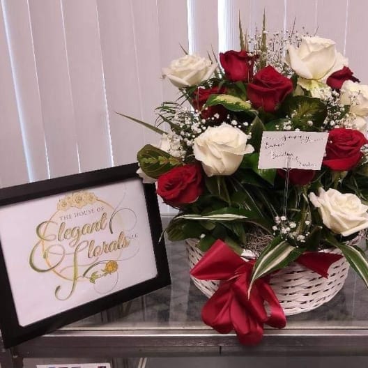 Basket arrangement of red and white roses with a red ribbon