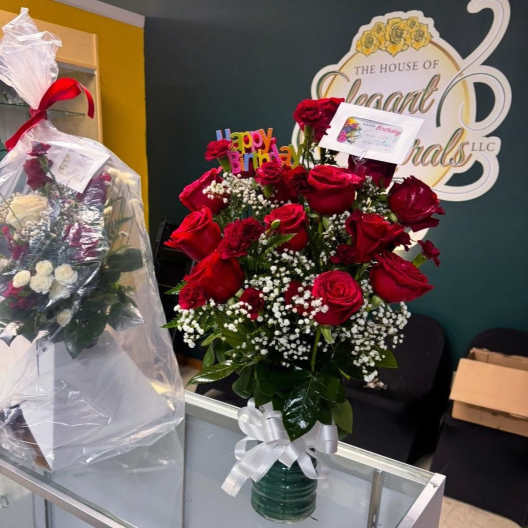 Red rose bouquet in a glass vase with baby's breath and a white ribbon