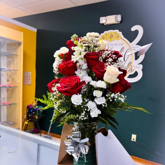 Red and white roses arranged in a glass vase with a silver bow