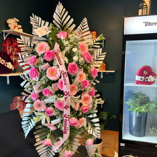 Pink rose and daisy standing spray with a memorial ribbon