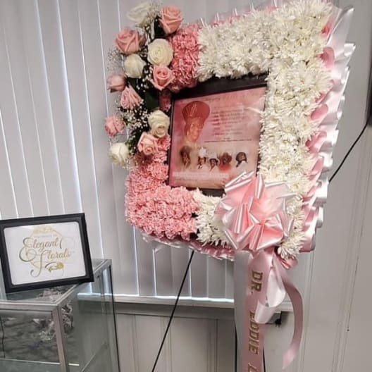 Standing floral tribute with pink and white flowers around a framed photo