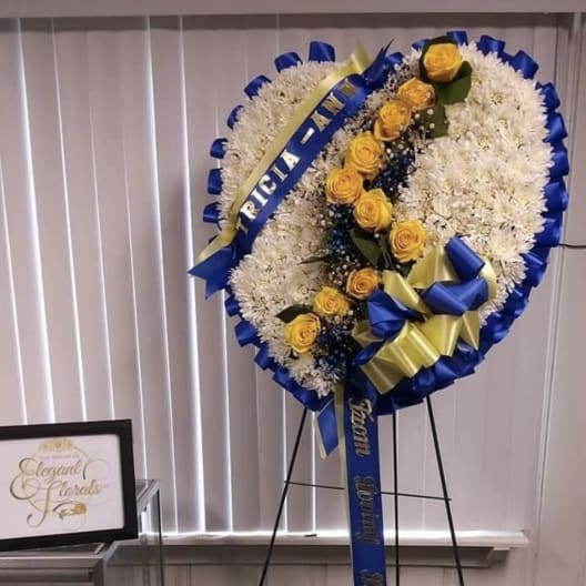 Standing floral wreath with white flowers and yellow roses on an easel