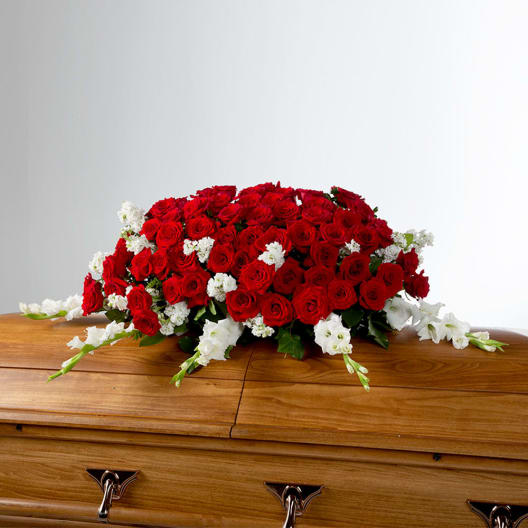Red and white floral spray arranged on a wooden casket