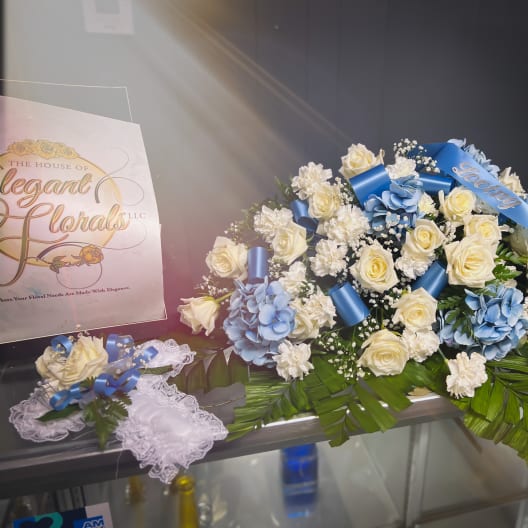 White roses and blue flowers arranged with ribbons on a table