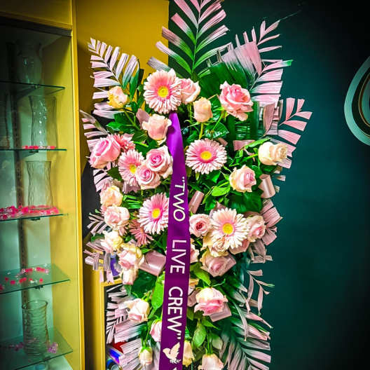 Standing floral spray with pink roses and gerbera daisies on an easel