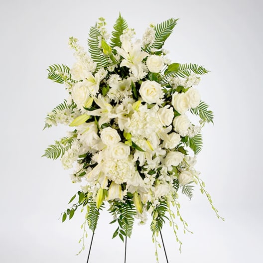 White floral standing spray with lilies and roses on a tripod easel
