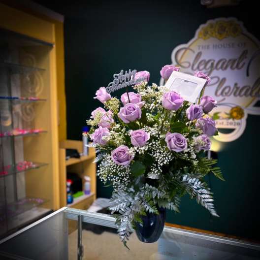 Lavender roses arranged in a dark vase with a small topper