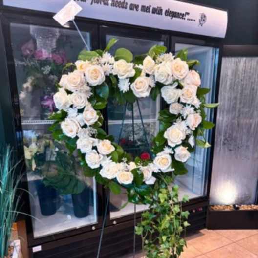 Heart-shaped white rose wreath on a standing easel with trailing ivy