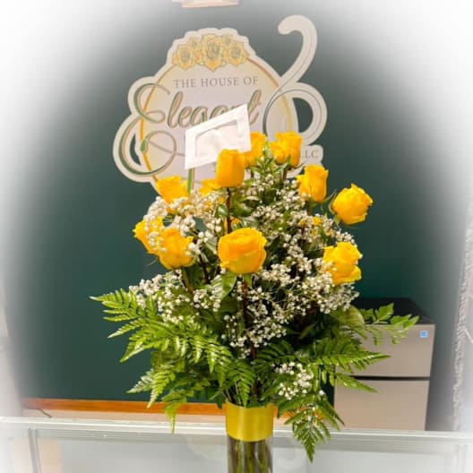Yellow roses in a clear glass vase with baby's breath