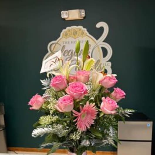 Pink roses and lilies arranged in a tall glass vase