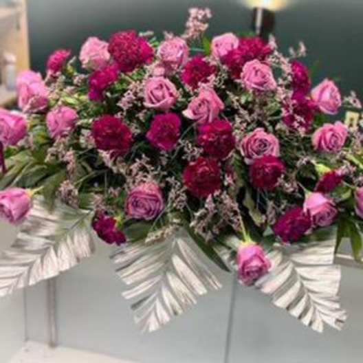 Pink and magenta rose arrangement on a white casket