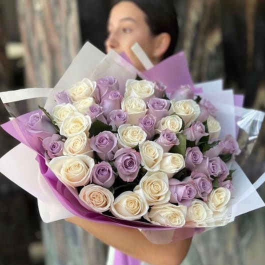 Bouquet of lavender and white roses wrapped in purple paper