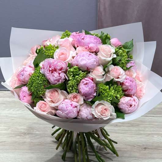 Bouquet of pink peonies and pale pink roses wrapped in white paper