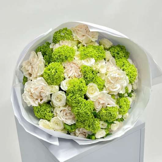 Bouquet of cream roses and bright green pom-pom flowers wrapped in white paper