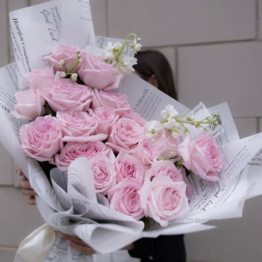 Large bouquet of pale pink roses wrapped in white paper