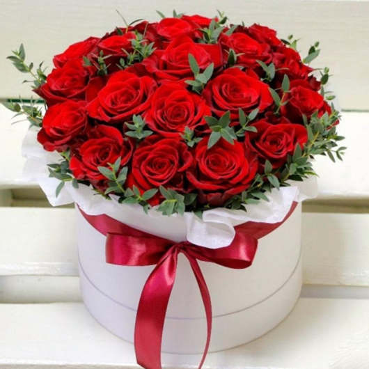 Red roses arranged in a white round box with a red ribbon