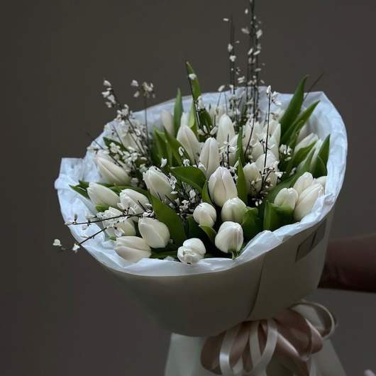 Bouquet of white tulips wrapped in white paper with a ribbon
