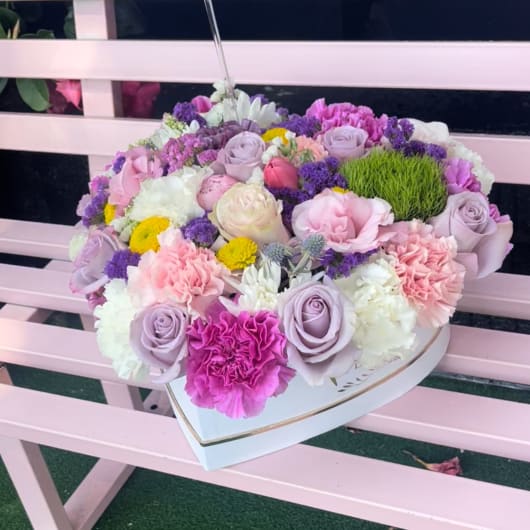 Heart-shaped box filled with pastel roses and carnations