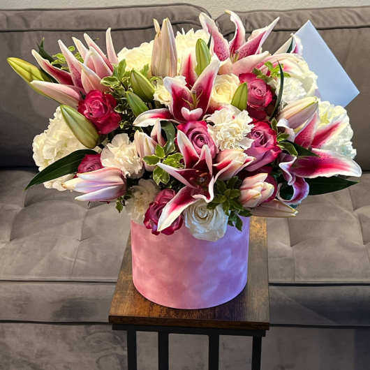 Bouquet of pink lilies and roses in a pink hatbox