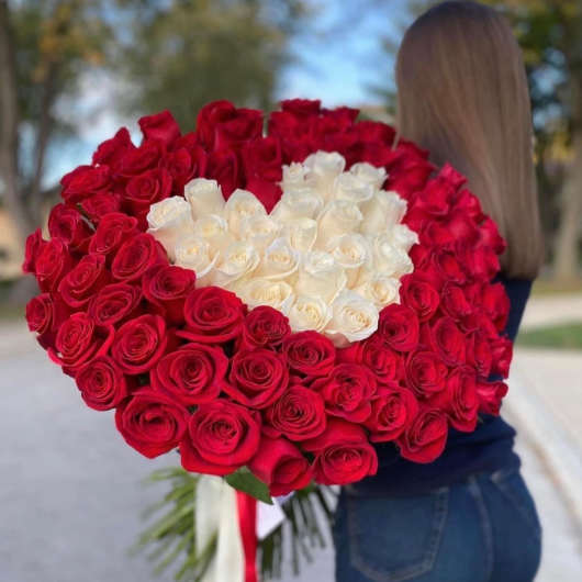 Large bouquet of red and white roses held by a person outdoors