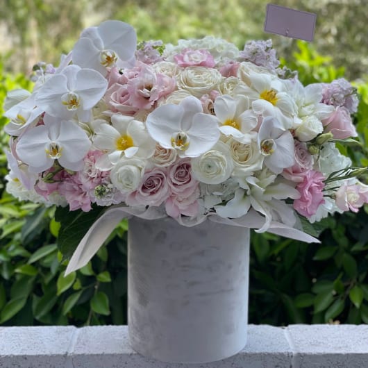 Pink and white floral arrangement in a tall gray vase